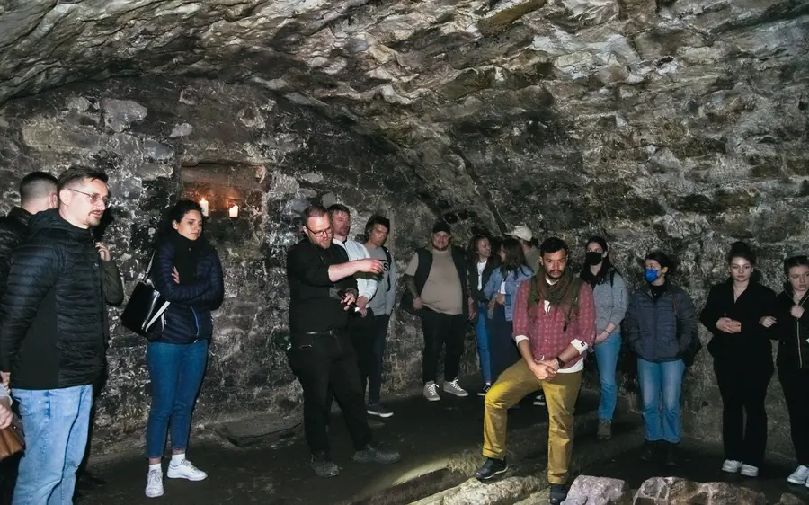 A tour group inside a stone chamber of the Edinburgh underground vaults